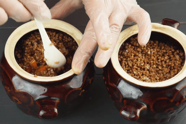  Затем добавить гречку, перемешать. Залить водой, чтобы она покрывала продукты на 1,5 см. Закрыть горшочки крышками.