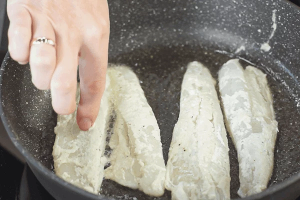 В сковороду налить оливковое масло, нагреть, обжарить рыбу по 2 минуты с каждой стороны, снять со сковороды. 