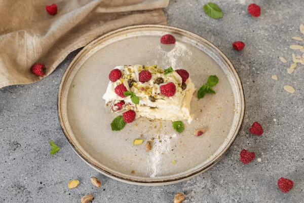 Готовый рулет оформить кремом, фисташковой пастой, свежей малиной, мятой, рублеными фисташками и хлопьями миндаля. 
