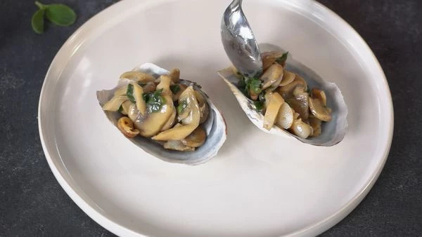 На тарелку для подачи выложить раковины. В них переложить обжаренного гуидака. Оформить листьями бораго. Приятного аппетита!
