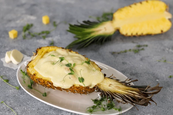 На блюдо для подачи выложить половинку ананаса. Оформить микрозеленью. 