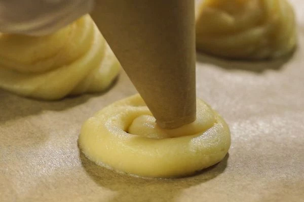 На застеленный пергаментом противень выдавить в виде шариков, диаметром с грецкий орех (можно сделать и по крупнее, тогда надо следить за временем приготовления).