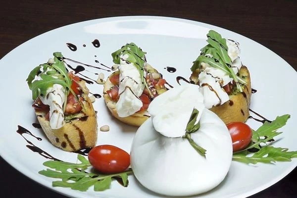 Каждую брускетту украсить салатом руккола, поперчить свежемолотым черным перцем. Сбрызнуть соусом крем-бальзамик.