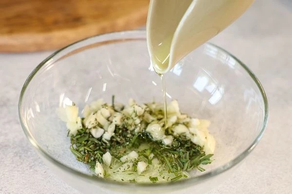 Раздавить, очистить и порубить 3 зубчика чеснока. Смешать рубленые травы с чесноком и оливковым маслом, посолить, поперчить и перемешать. 
