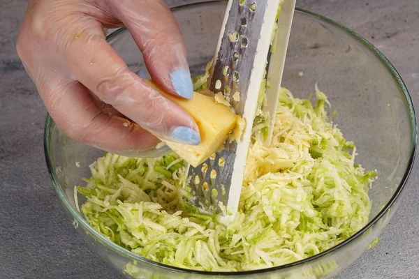 В глубокую чашку натереть на крупной терке кабачок и сыр.