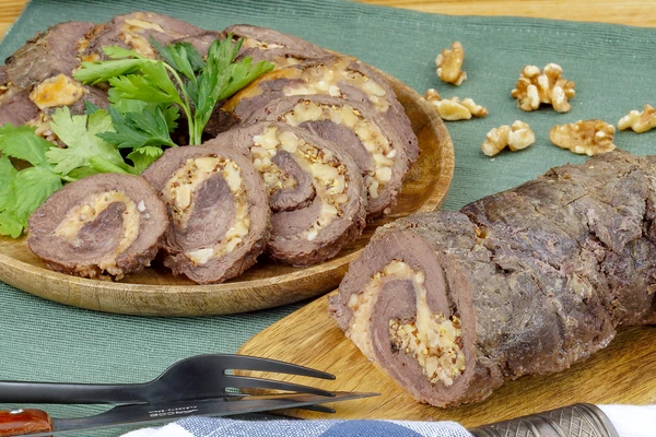 С готового рулета снять фольгу, удалить нитки, нарезать на порционные кусочки и украсить зеленью.